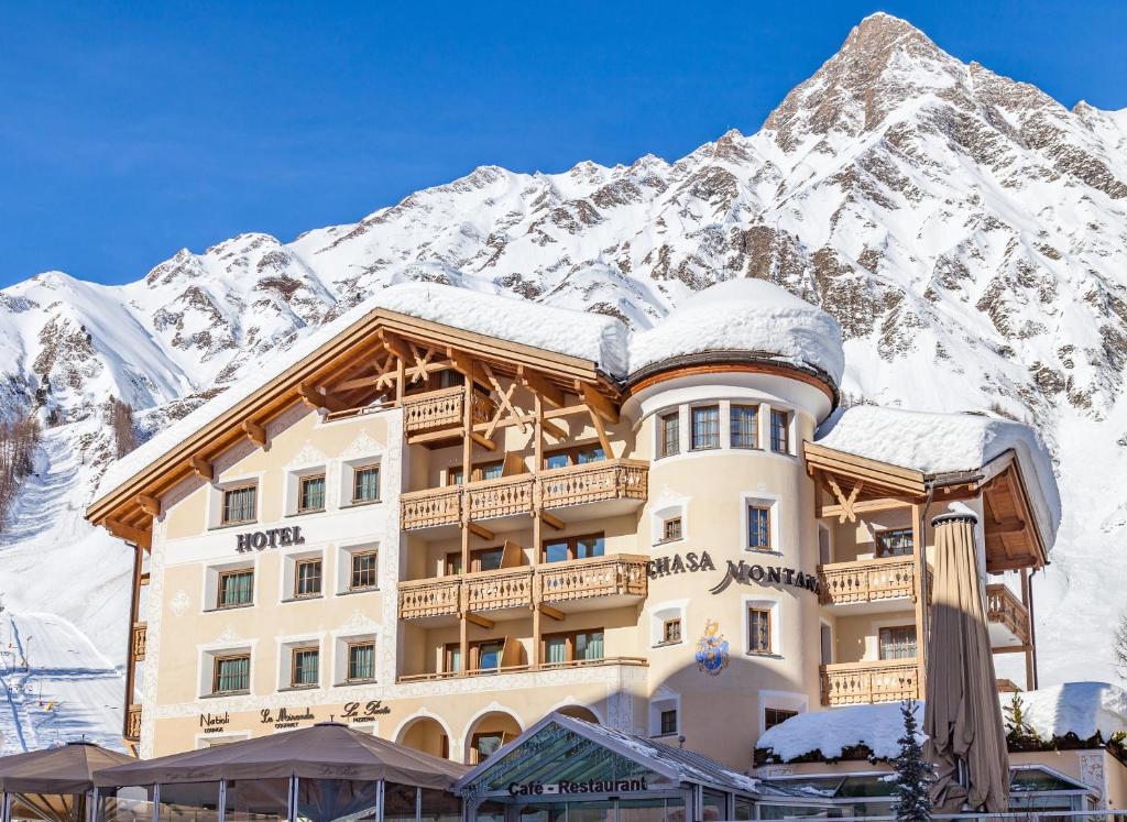 a hotel in front of a snow covered mountain at Relais & Châteaux Chasa Montana in Samnaun