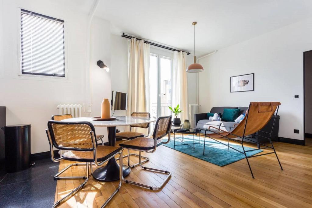 uma sala de estar com uma mesa e cadeiras e um sofá em Joie Paris Opéra - Gare St Lazare em Paris