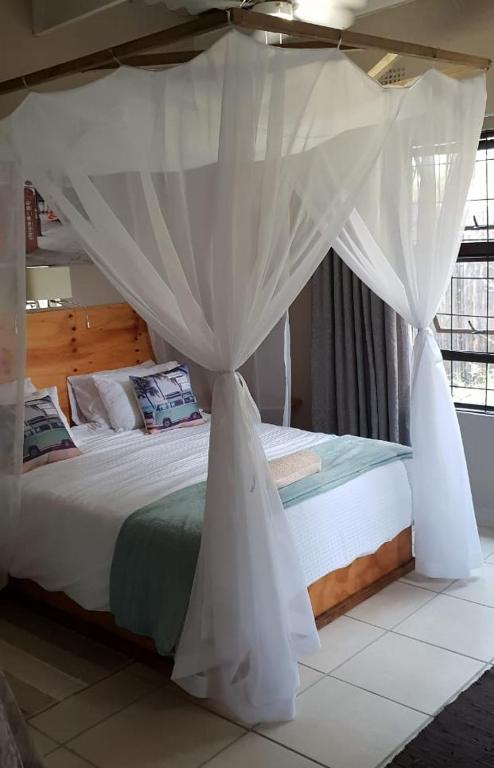a bedroom with a white bed with a canopy at Ma's Cottage in Sodwana Bay