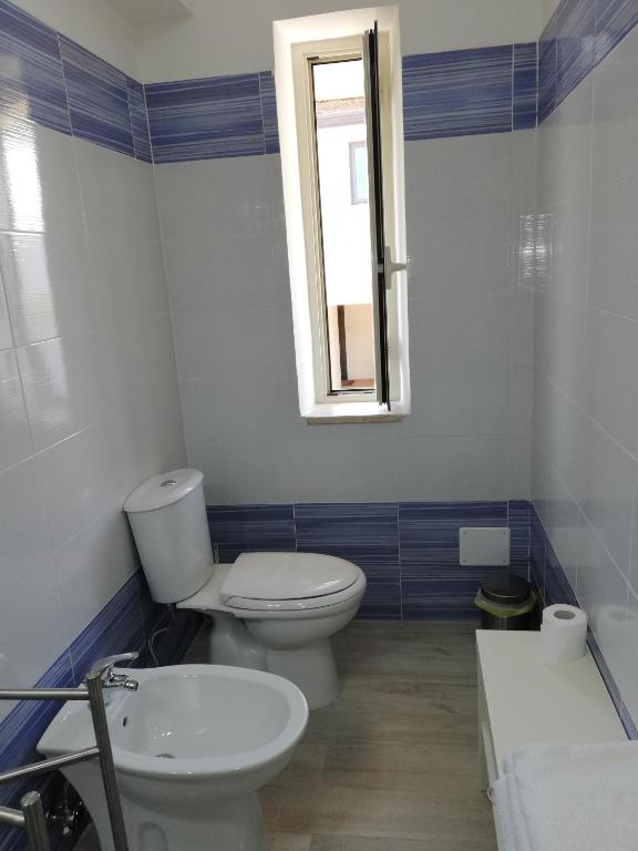 a bathroom with a toilet and a sink and a window at Akron B&B in SantʼAlessio Siculo