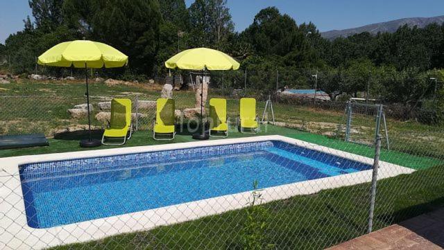 einen Pool mit Stühlen und Sonnenschirmen neben in der Unterkunft La Cabaña del Alberche in Navaluenga