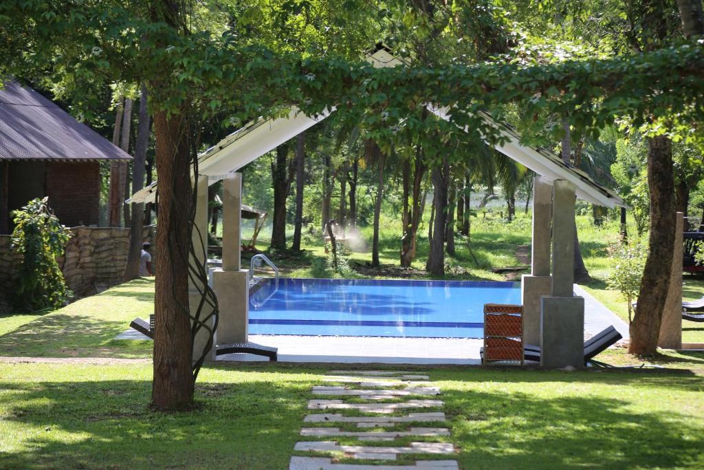 einen Pool im Garten mit Pavillon und Bäumen in der Unterkunft Athena Lake in Dambulla