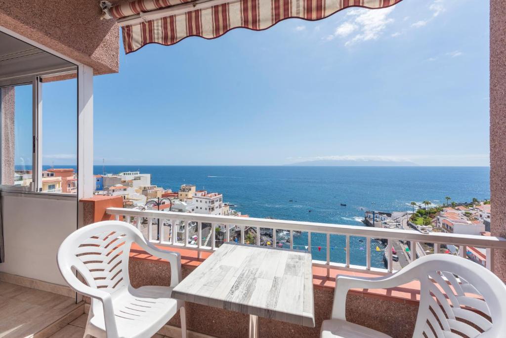 een balkon met een tafel en stoelen en de oceaan bij Bahia suite in Puerto de Santiago