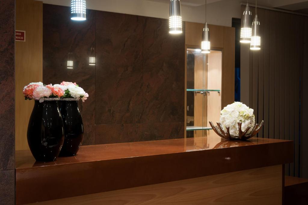 two vases with flowers on a counter in front of a mirror at Mondim AL & Spa in Mondim de Basto