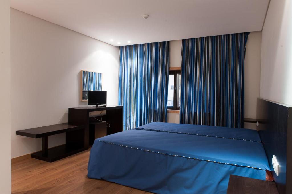 a bedroom with a blue bed and a desk at Mondim AL & Spa in Mondim de Basto