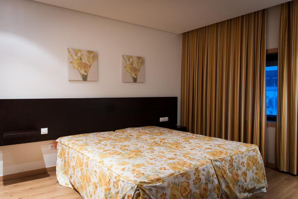 a bedroom with a bed and two paintings on the wall at Mondim AL & Spa in Mondim de Basto