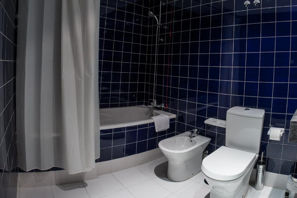 a blue tiled bathroom with a toilet and a bath tub at Mondim AL & Spa in Mondim de Basto