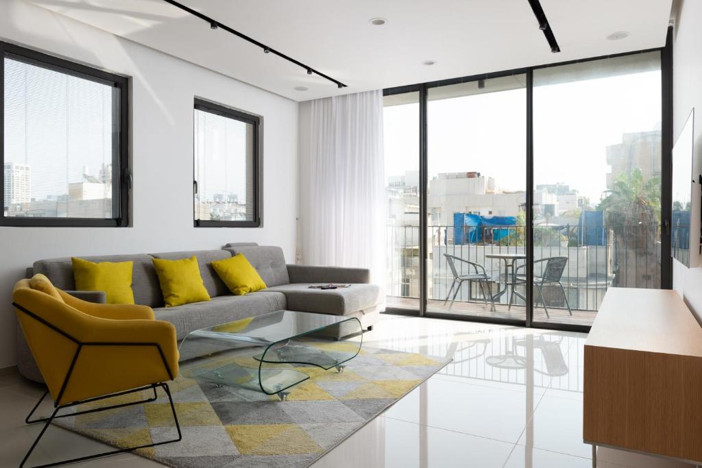 a living room with a couch and yellow pillows at Luxury 2bdrm balcony & parking close to the Beach in Tel Aviv