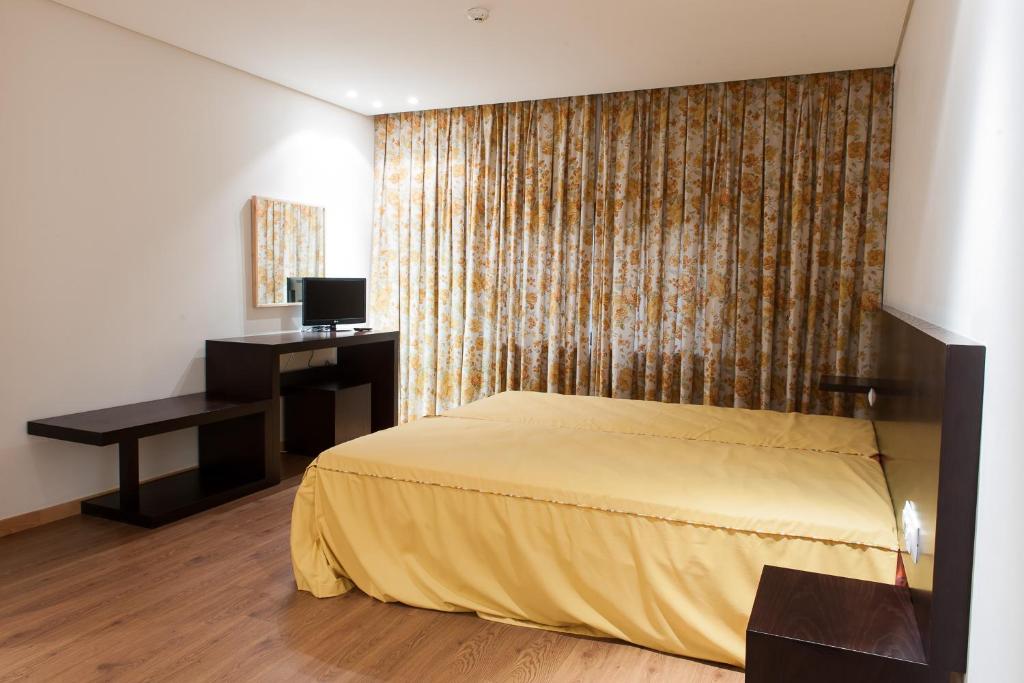 a bedroom with a bed and a desk and a television at Mondim AL & Spa in Mondim de Basto