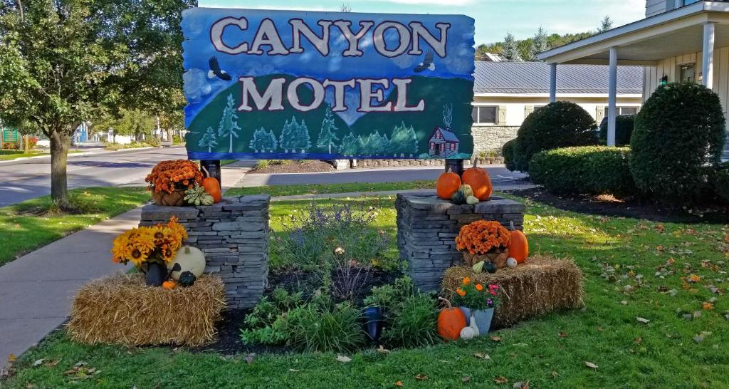 a sign for a campion motel with pumpkins and flowers at Canyon Motel in Wellsboro