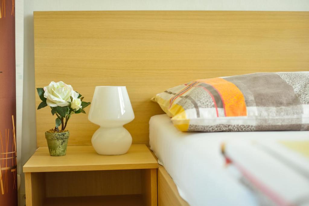 una cama con un jarrón blanco y una flor sobre una mesa en Zimní Stadion Tábor en Tábor