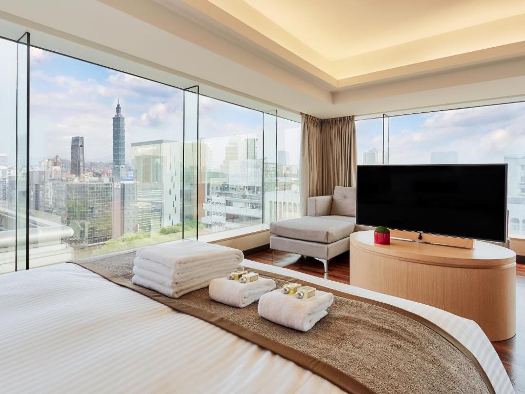 a bedroom with a large bed with a large window at Eastin Taipei Hotel in Taipei