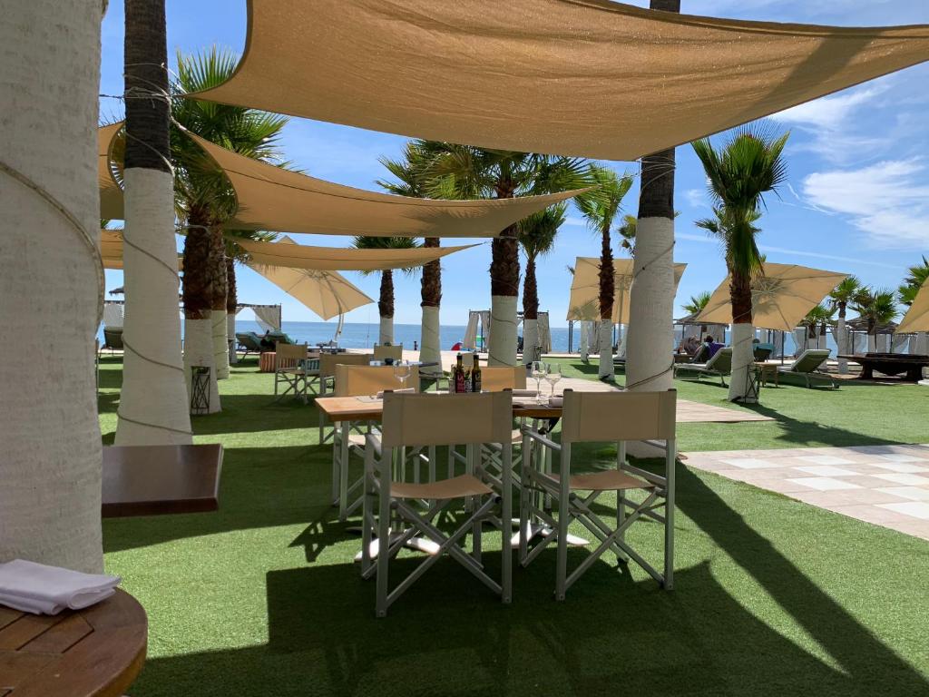 stół i krzesła pod baldachimem z palmami w obiekcie Los Flamingos Tee 6 w mieście Estepona