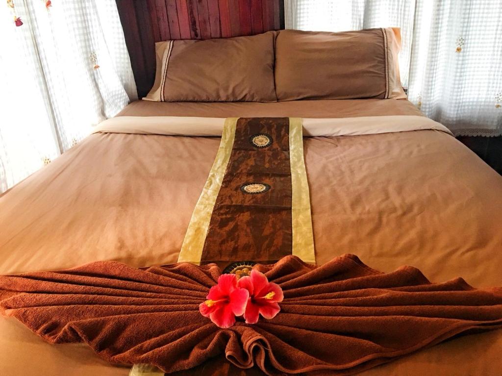 a bed with a dress with a red flower on it at Phi Phi Green Hill Resort in Phi Phi Don