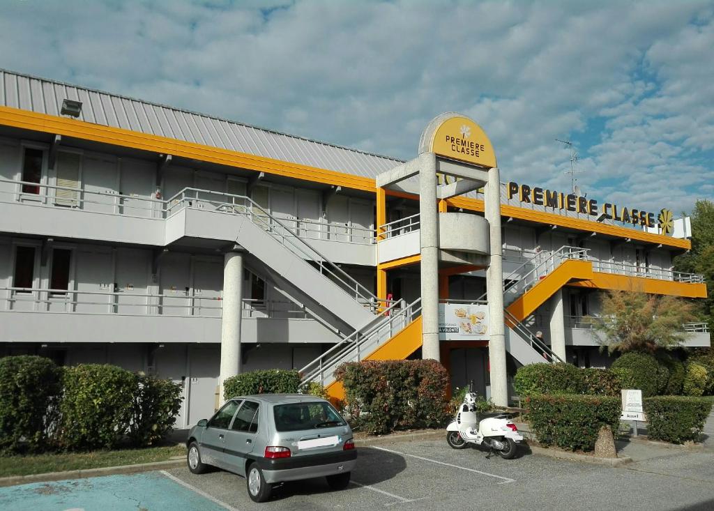 a car parked in a parking lot in front of a building at Premiere Classe Grenoble Sud - Gieres Universite in Gières