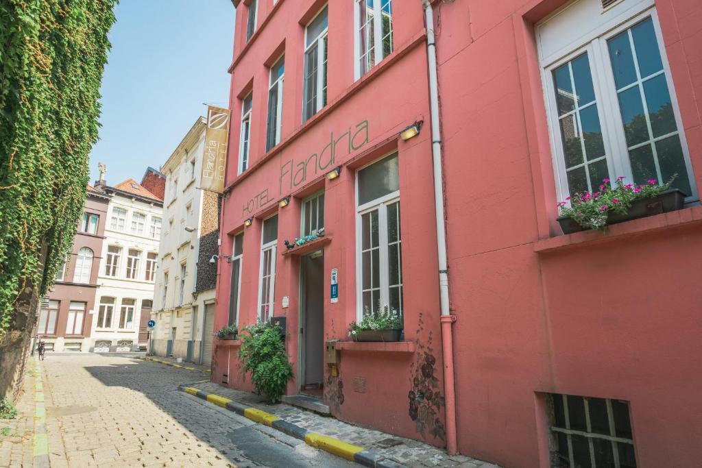 a red building on a street with flowers in the window at Flandria Hotel in Ghent