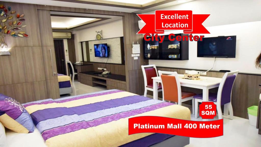 a room with a bed and a table and a tv at Family Suite Room Pratunam in Bangkok