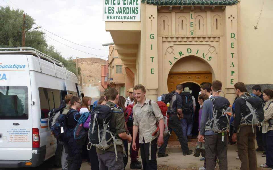 a group of people waiting to get on a bus at gîte les jardins in Goulmima