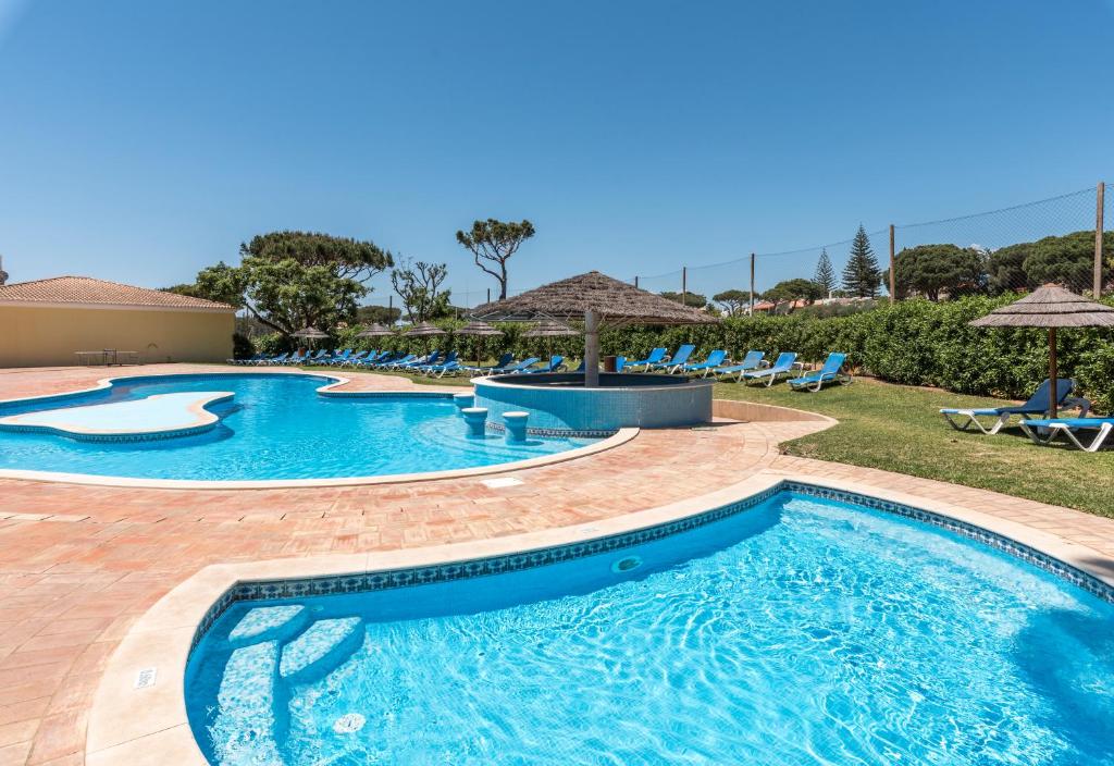a pool at a resort with chairs and umbrellas at Browns Sports Resort in Vilamoura