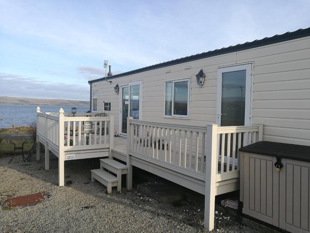 a tiny house with a porch and stairs next to the water at Oor wee hoose in Leswalt