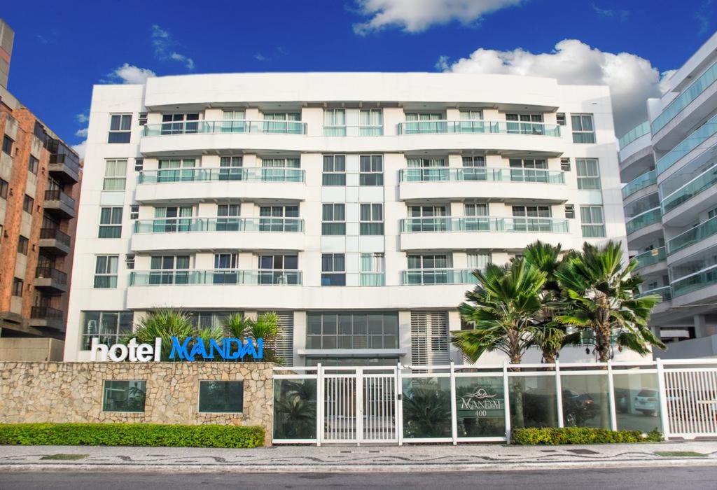 a hotel navan building with palm trees in front of it at Mandai Flat Hotel in Cabo Frio