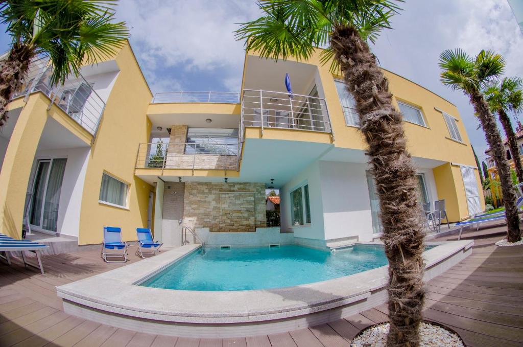 a house with a swimming pool and palm trees at Villa Danex Superior in Umag