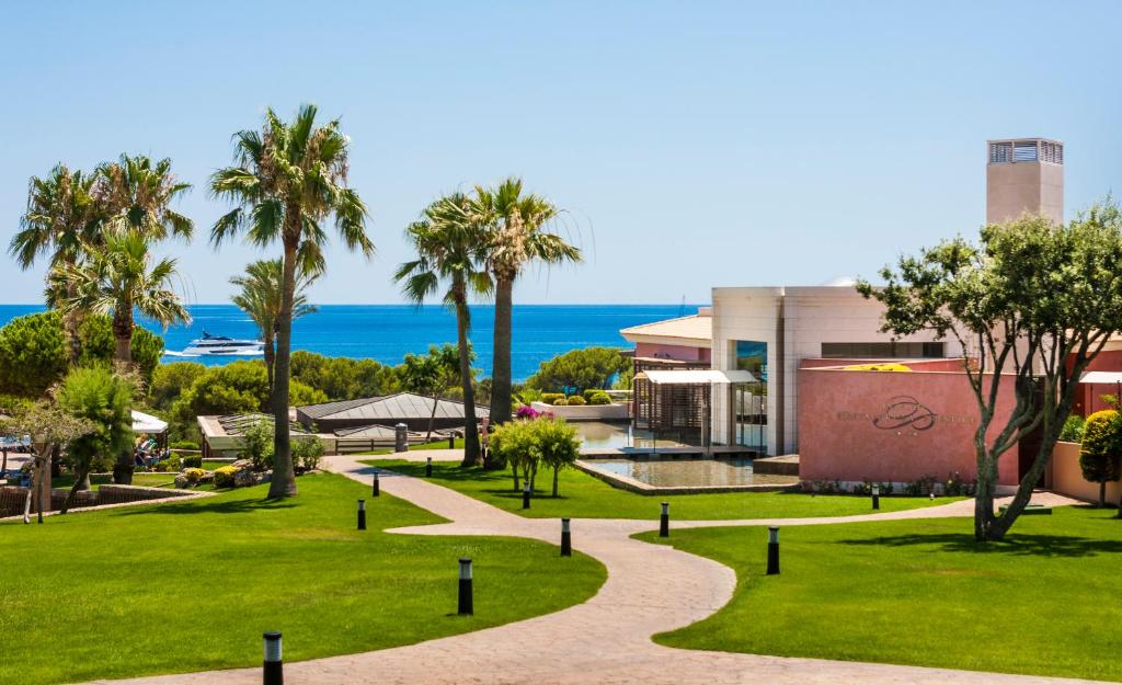 a park with palm trees and the ocean in the background at Insotel Punta Prima Prestige Suites & Spa in Punta Prima