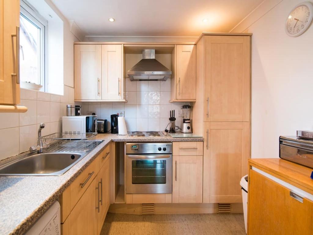a kitchen with wooden cabinets and a sink at Long Stay Reduced Rates 3P in Manchester