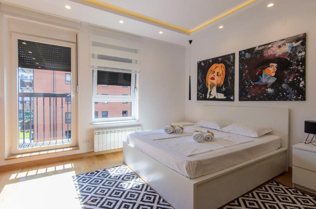 una camera bianca con un letto e due finestre di Sava Smart Apartment a Belgrado