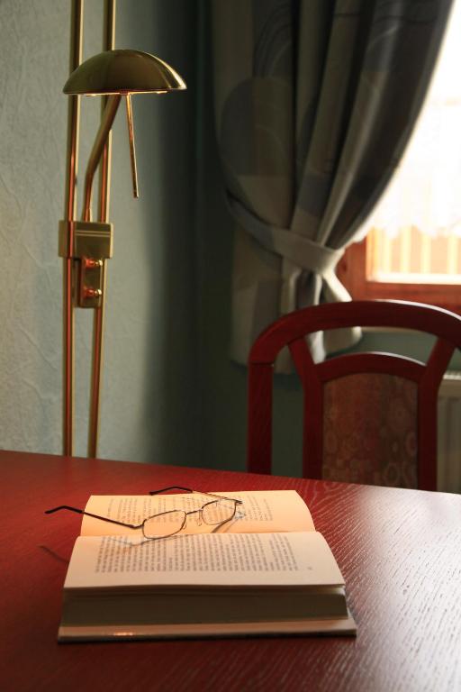 a book sitting on a table with a lamp and a book gmaxwell gmaxwell gmaxwell at Hotel Zur Fernmühle in Ziegenrück