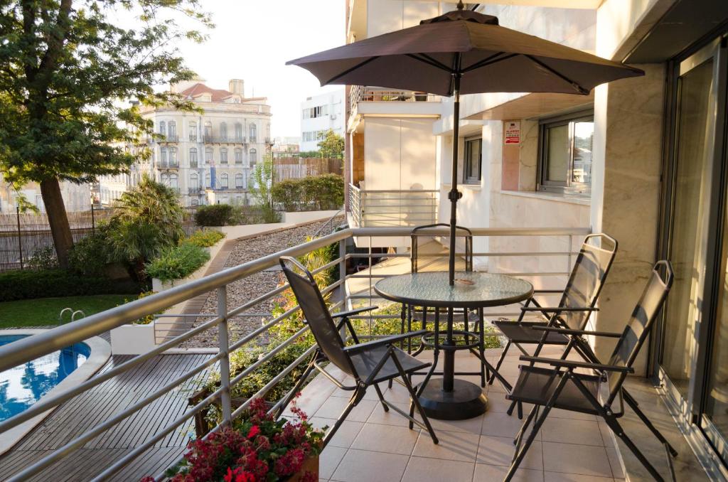 リスボンにあるALTIDO Graca Luminous 2-BR Apartment with Terraceのバルコニー(テーブル、椅子、パラソル付)