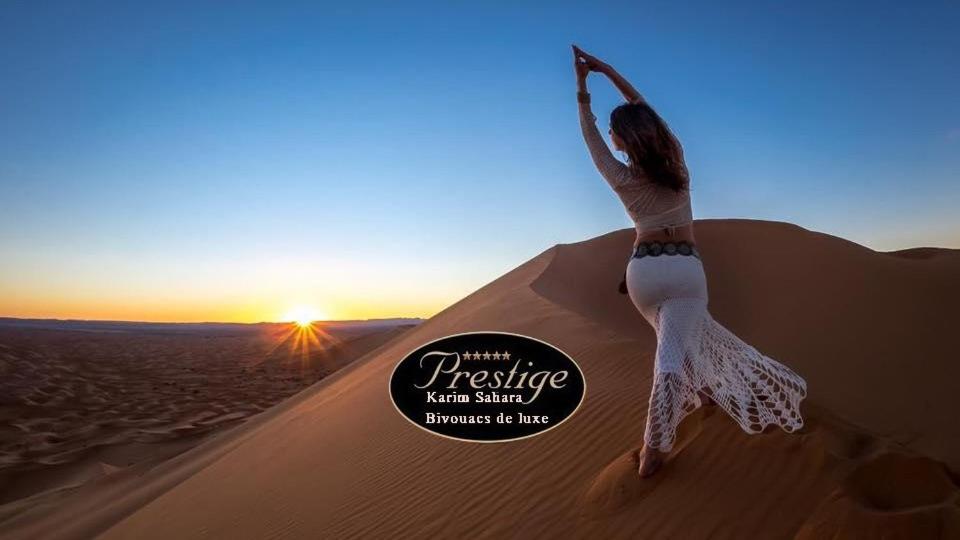a woman standing on a sand dune in the desert at Karim Sahara Prestige in Zagora