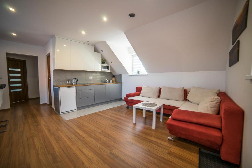 a living room with a red couch and a kitchen at Apartament Leśna in Limanowa