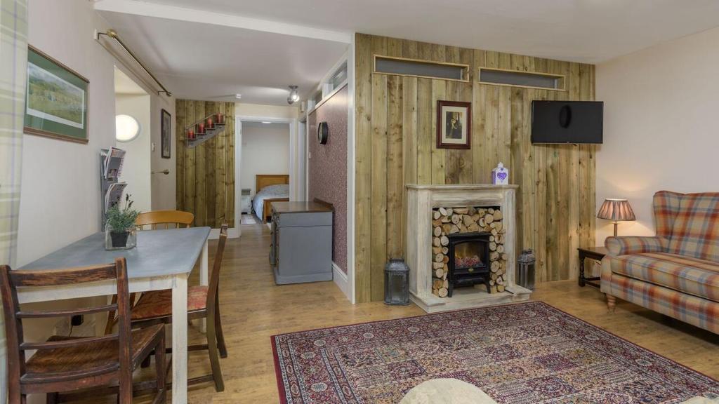 a living room with a table and a fireplace at Poppy's Place Cupar in Cupar