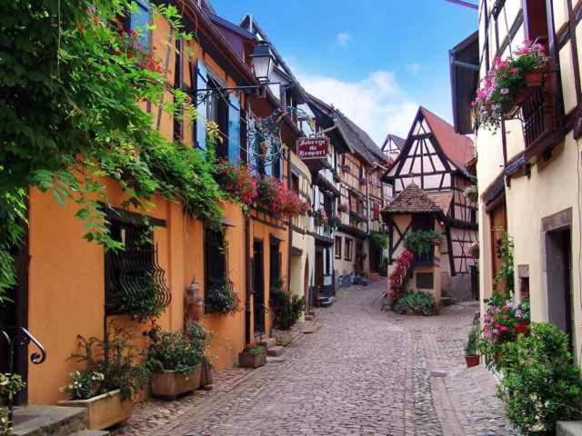 een geplaveide straat in een oude stad met gebouwen bij Auberge du Rempart in Eguisheim