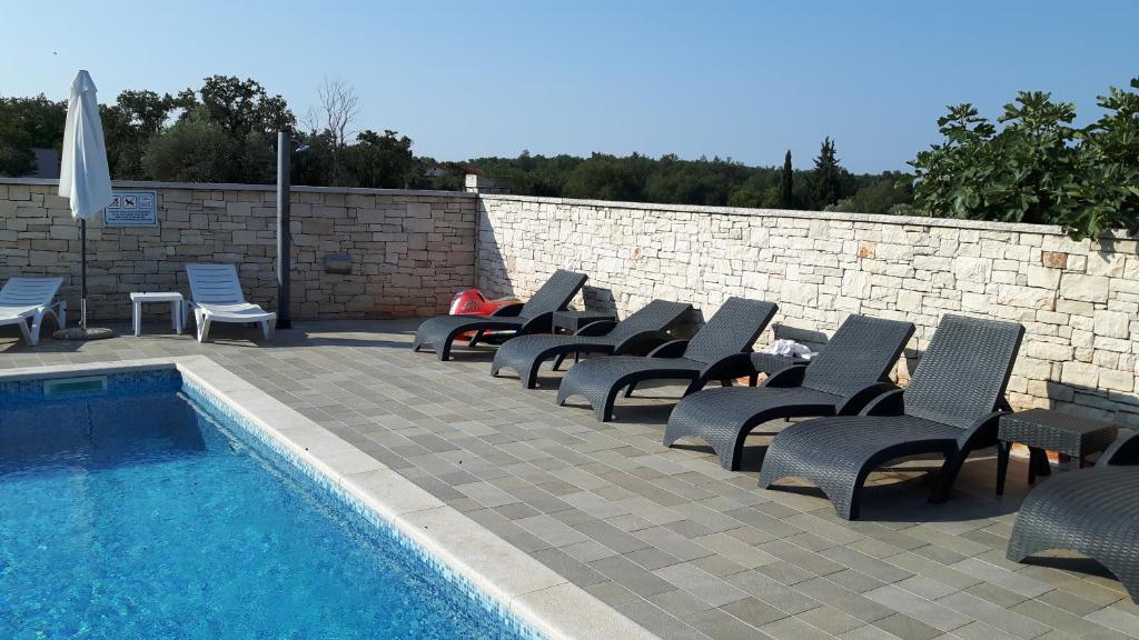 a row of lounge chairs next to a swimming pool at Apartments Villa Adamović in Umag