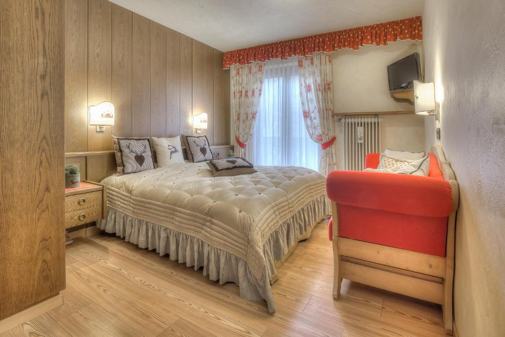 una camera con letto e sedia rossa di Hotel Luianta a Colfosco