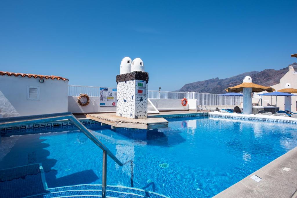 una piscina con un faro al lado de un edificio en Vigilia Park, en Puerto de Santiago