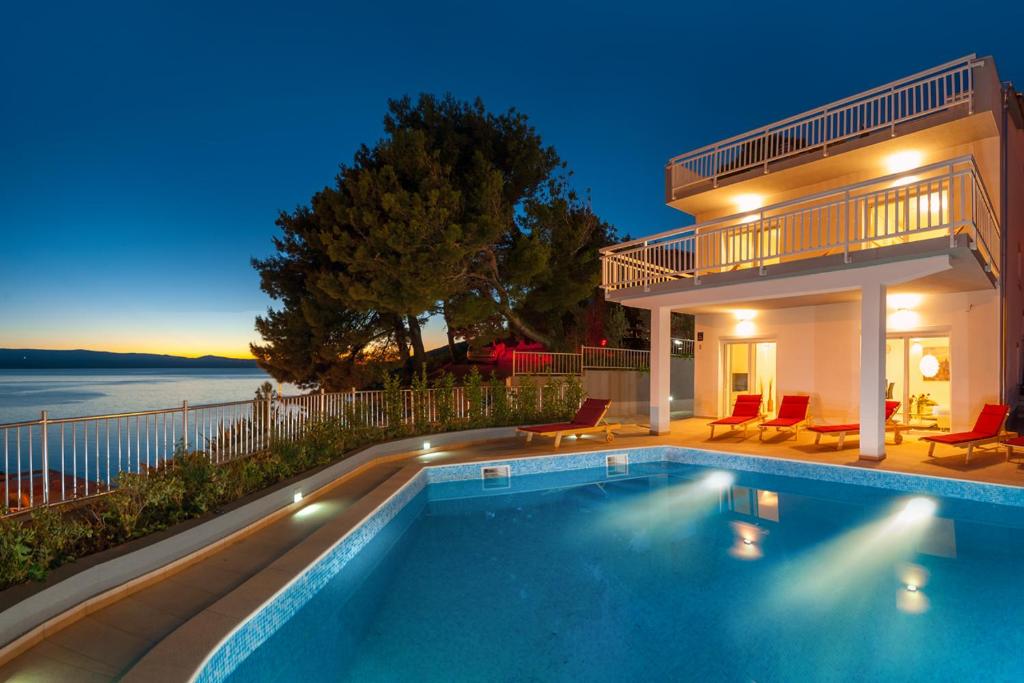 a swimming pool in front of a house at Magnificent Villa with Pool,Sea View,BBQ,Sauna in Mimice