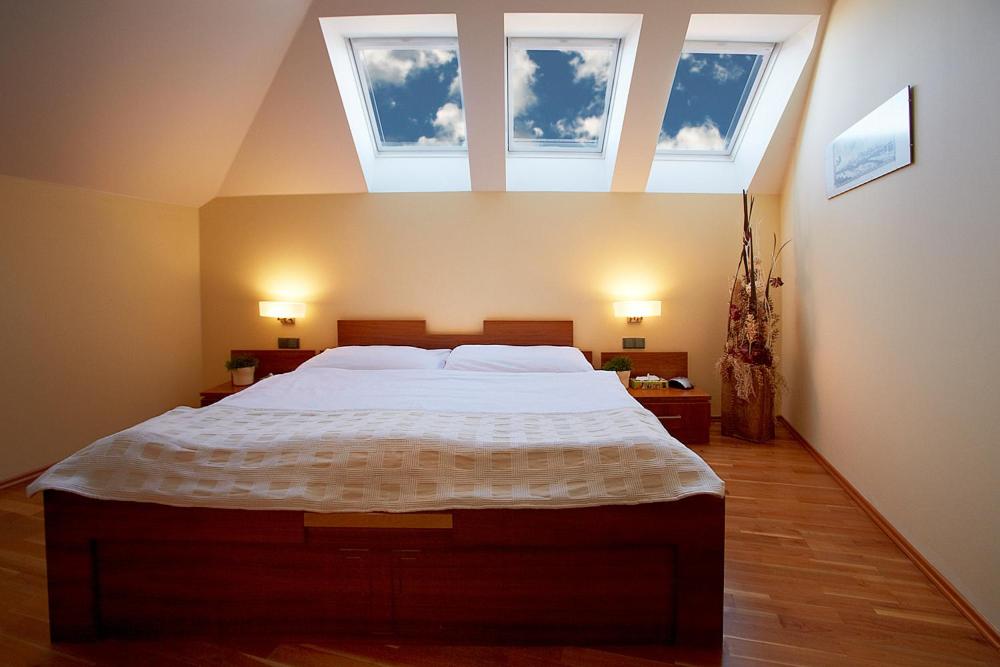 a bedroom with a large bed with two windows at Hotel Penzion Na Hradě in Olomouc