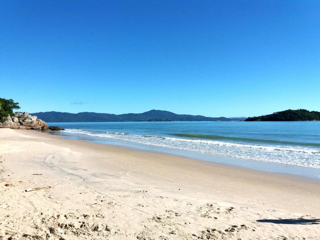 una playa de arena con el océano en el fondo en Canasvieiras - Residencial Costa do Mar, en Florianópolis