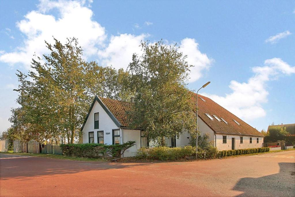 uma casa branca com um telhado vermelho numa rua em Buurtskap 't Buurtje em Schagerbrug