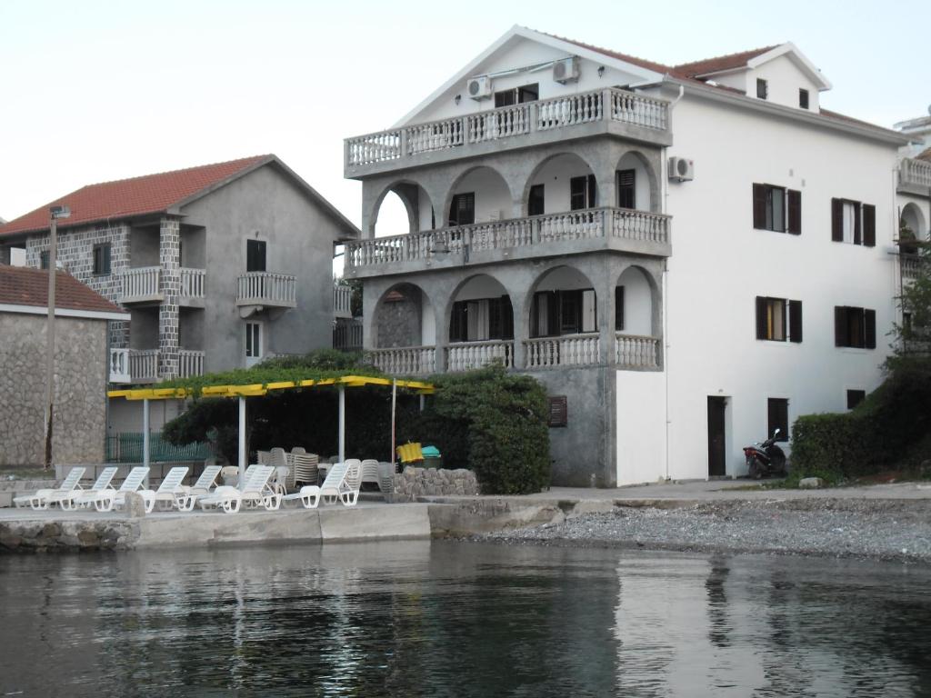 een groot wit gebouw met witte stoelen naast het water bij Apartments Petrović in Tivat