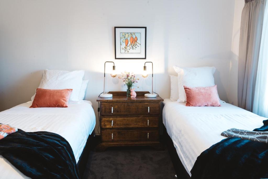 Un dormitorio con dos camas y un tocador con flores. en Southlynne en Launceston
