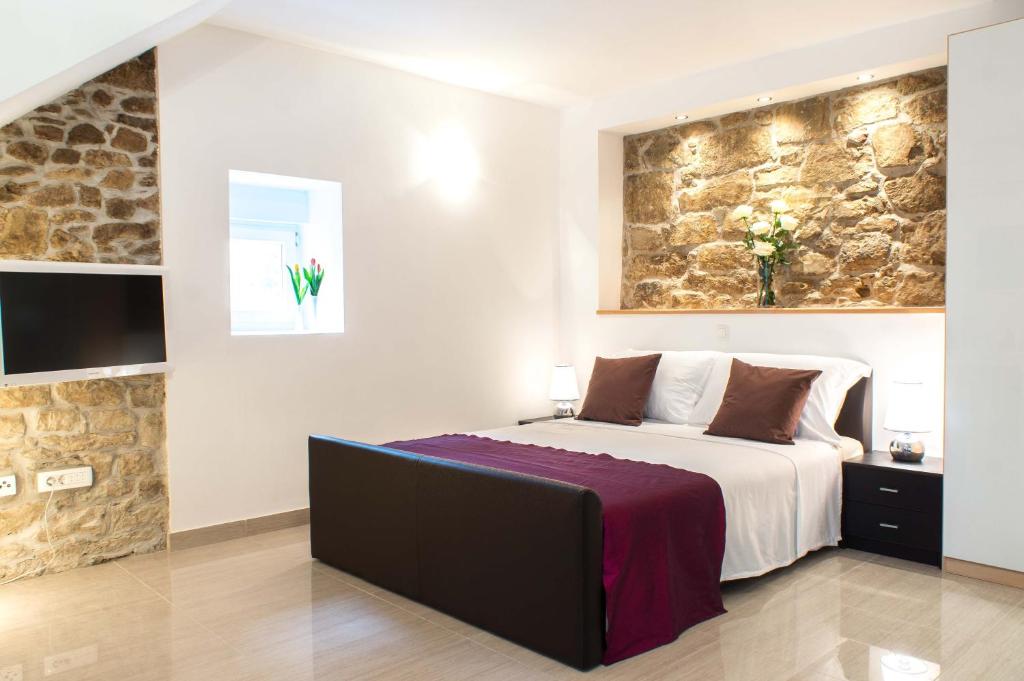 a bedroom with a large bed and a stone wall at Split Allure Apartments in Split