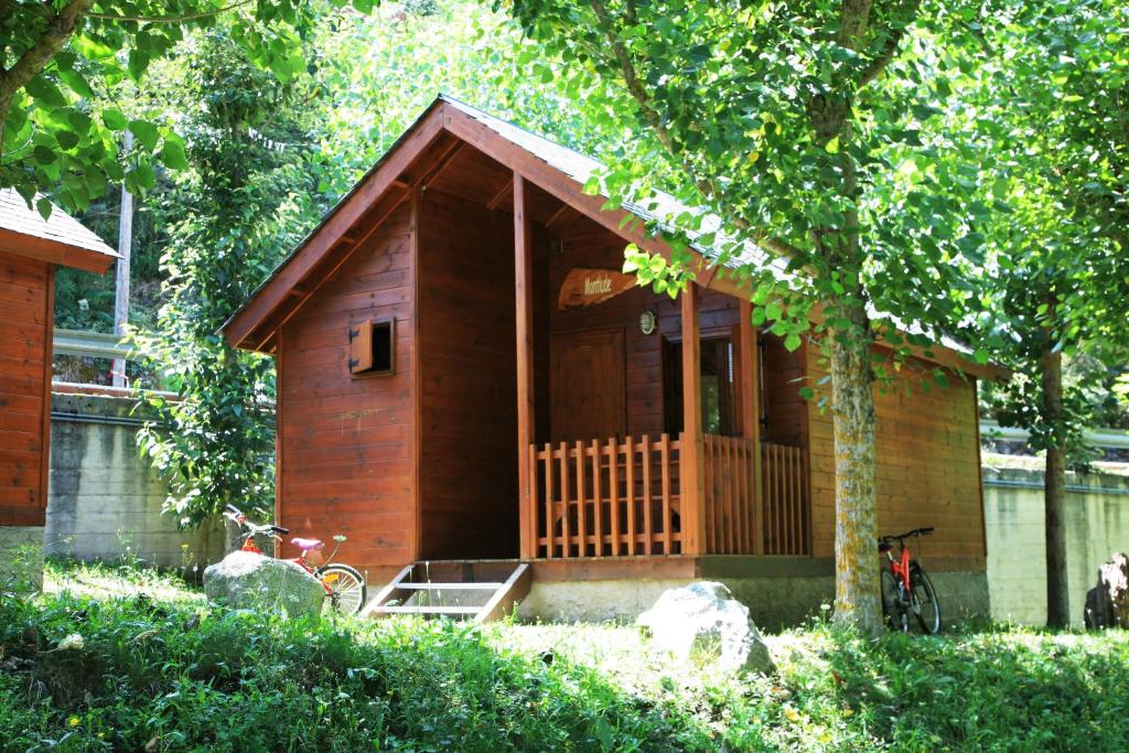 una pequeña casa de madera con porche y bicicleta en Camping Forcanada, en Era Bordeta