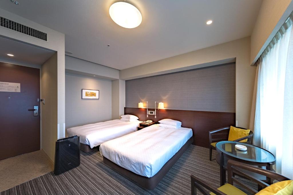 a hotel room with two beds and a table at Centrair Hotel in Tokoname
