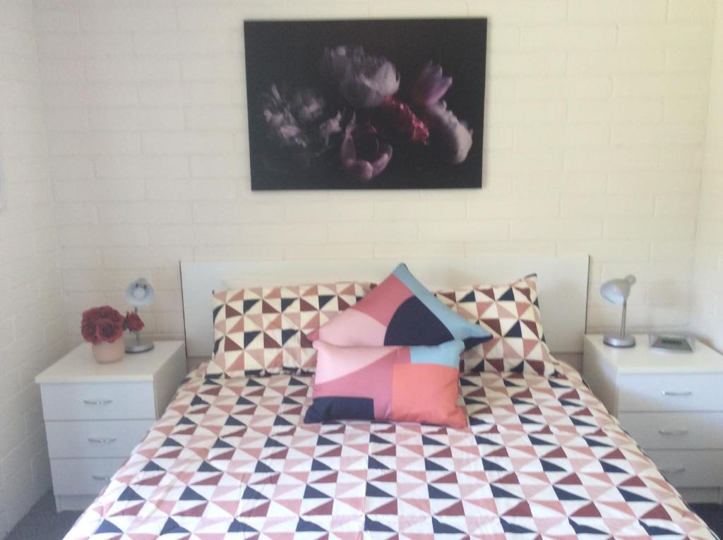 een slaapkamer met een bed met kleurrijke kussens bij Aquarius Batehaven in Batemans Bay