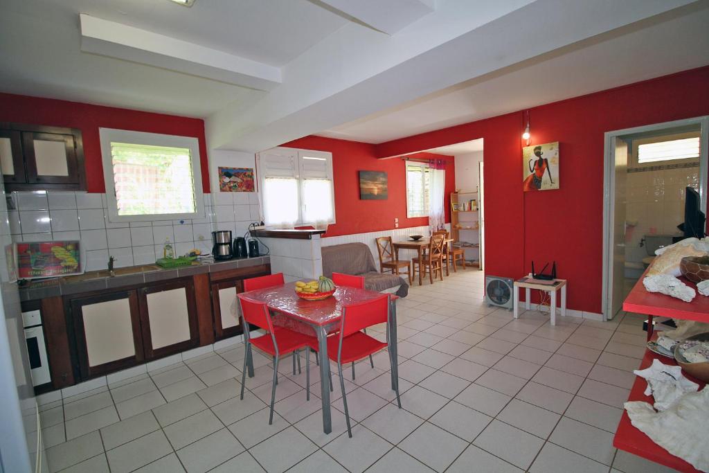 a kitchen with red walls and a table in a room at CHEZ JOJO in Sainte-Anne