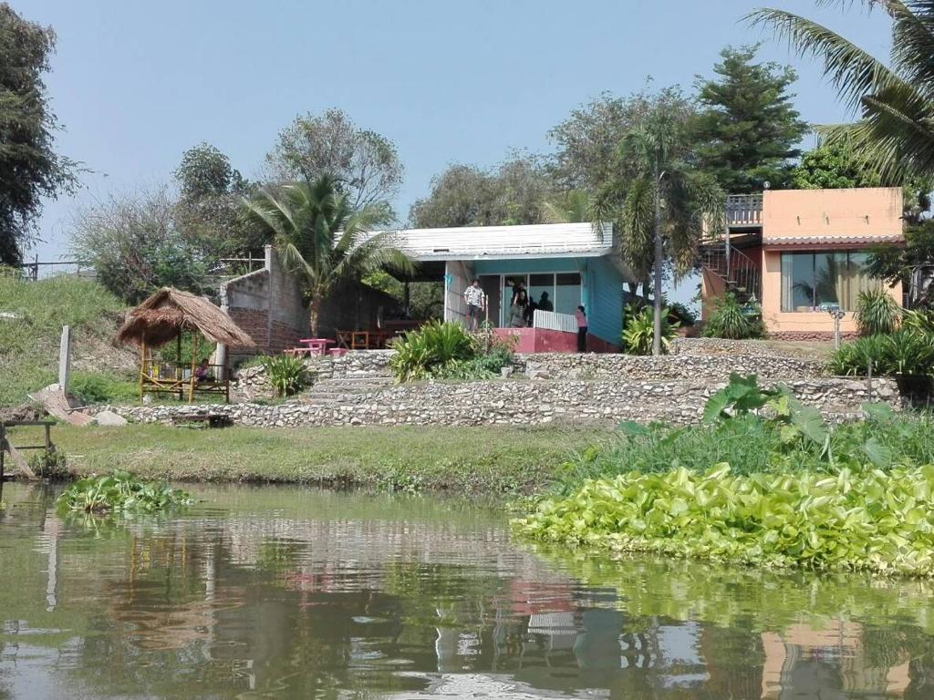 a house next to a body of water at Baan Din Baramee Resort in Kamphaeng Phet